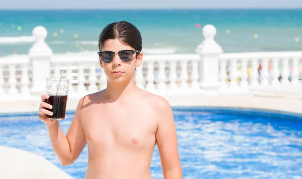 スマートの顔は深刻な思考に自信を持って式にビーチでのスイミング プールで休日にソーダを飲む若い子 — ストック写真