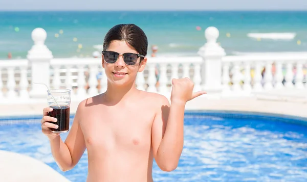 指していると幸せそうな顔を笑顔で側まで親指で示すビーチでプールで休日にソーダを飲む若い子 — ストック写真