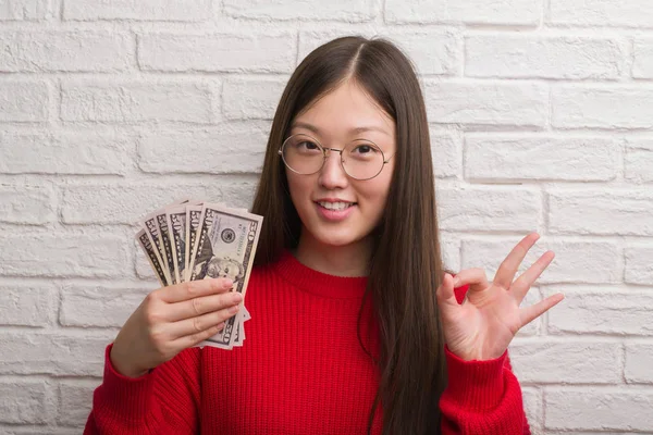 Mulher Chinesa Nova Sobre Parede Tijolo Segurando Dólares Fazendo Sinal — Fotografia de Stock