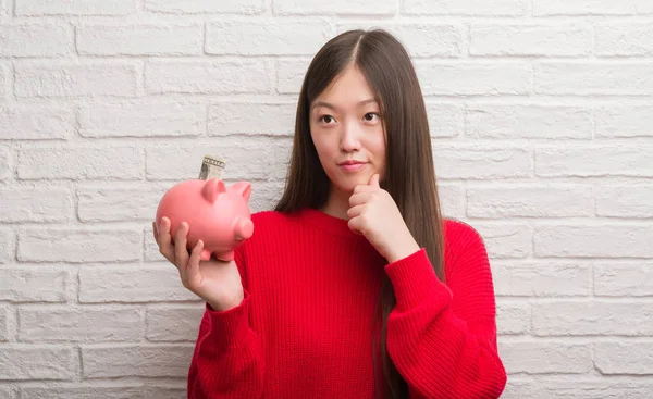 Joven Mujer China Sobre Pared Ladrillo Sosteniendo Alcancía Cara Seria — Foto de Stock