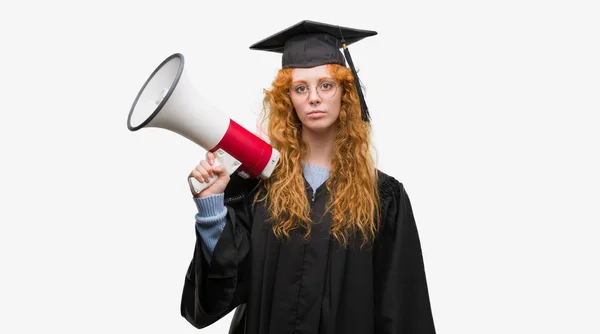 身に着けている赤毛の若い学生女性卒業スマートの顔は深刻な思考に自信を持って式に制服持株メガホン — ストック写真