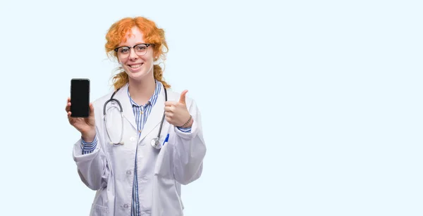 Jovem Mulher Médica Ruiva Mostrando Smartphone Feliz Com Grande Sorriso — Fotografia de Stock