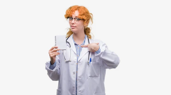 Jovem Ruiva Médico Mulher Segurando Notebook Branco Com Rosto Surpresa — Fotografia de Stock