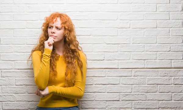 Junge Rothaarige Frau Steht Über Ziegelmauer Ernstes Gesicht Über Frage — Stockfoto