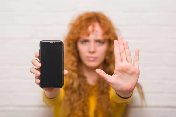 Junge Rothaarige Frau Sitzt Über Ziegelmauer Und Zeigt Smartphone Mit — Stockfoto