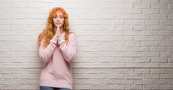 Unga Rödhårig Kvinna Som Står Över Tegelvägg Bedjande Med Händerna — Stockfoto