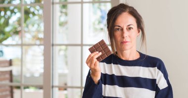 Orta yaşlı kadın çikolata kendine güvenen bir ifade ile acımak yüz düşünme ciddi yeme