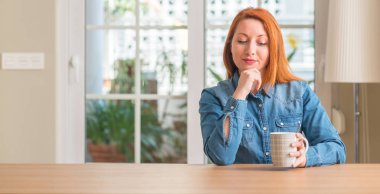 Bir fincan kahve ciddi bir yüz düşünme hakkında soru, çok karışık fikir tutan Kızıl saçlı kadın