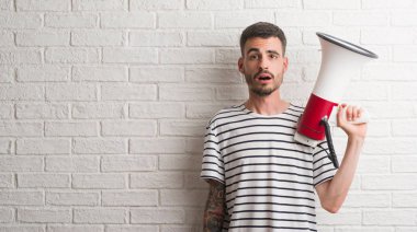 Megafon bir sürpriz yüz, korkuyor ve heyecanlı korku ifadesi ile şok korkmuş tutan genç yetişkin adam