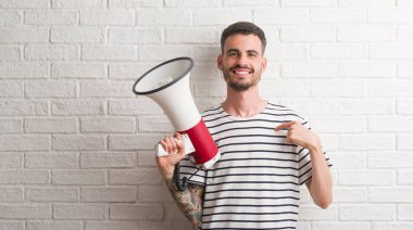 Megafon sürpriz yüz işaret parmağı kendisine tutan genç yetişkin adam