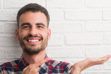 Genç yetişkin adam beyaz tuğla duvar el ve parmak ile işaret çok mutlu üzerinde ayakta