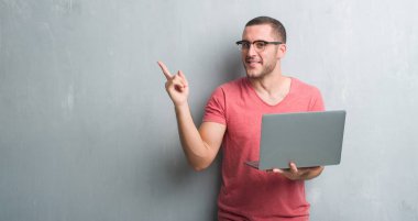 Bilgisayar dizüstü el ve parmak ile tarafına işaret çok mutlu kullanarak gri grunge duvar üzerinde beyaz delikanlı