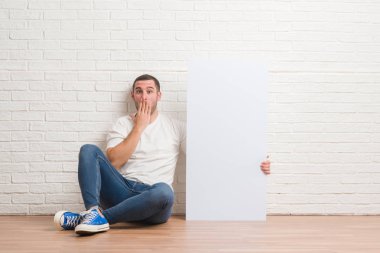 Hata, korku, sessizlik içinde gizli kavramı korkmuş ifade için utanç ile beyaz tuğla duvar holding şişe su kapak ağız üzerinde el ile oturan genç beyaz adam şok