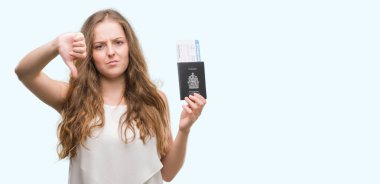 Young blonde woman holding passport of canada and boarding pass with angry face, negative sign showing dislike with thumbs down, rejection concept clipart