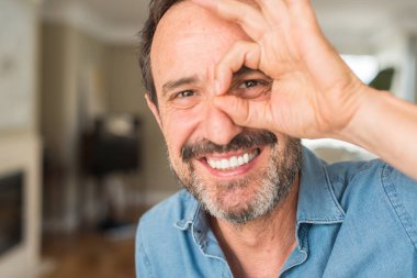 Orta yaş erkek ok işareti ile el parmaklarının arasından seyir göze yapıyor gülümseyen mutlu yüz ile dizüstü evde kullanma