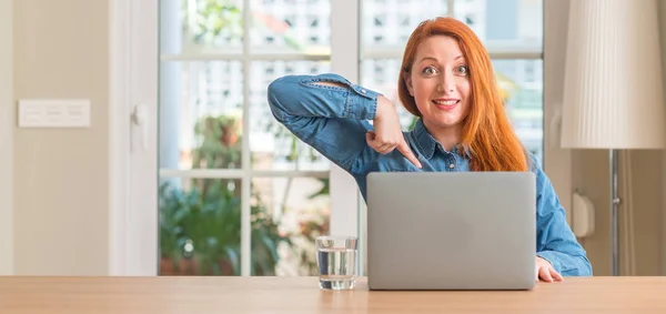 Pelirroja Mujer Usando Ordenador Portátil Casa Con Cara Sorpresa Señalando —  Fotos de Stock