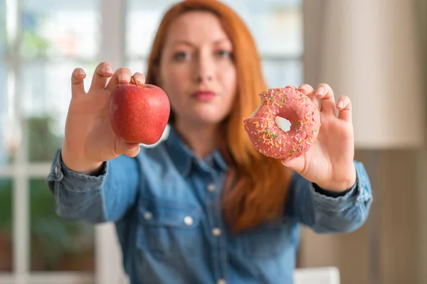 Rossa Donna Sceglie Tra Mela Ciambella Con Espressione Fiduciosa Sul — Foto Stock