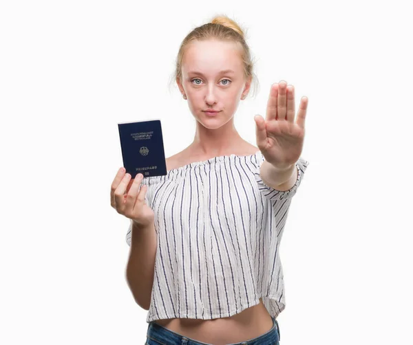 ブロンド十代の若者女性持株パスポート ドイツの防衛のジェスチャー 深刻な自信を持って式に一時停止の標識をやって開いた手 — ストック写真