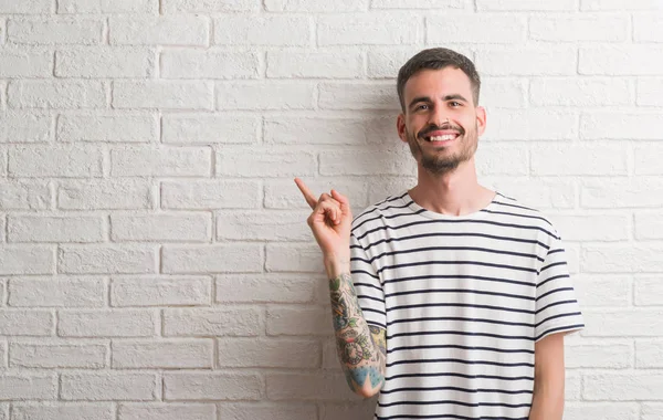 Homem Adulto Jovem Sobre Parede Tijolo Branco Muito Feliz Apontando — Fotografia de Stock