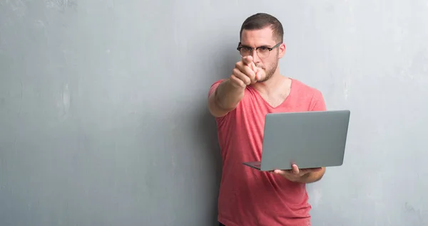 Young Caucasian Man Grey Grunge Wall Using Computer Laptop Pointing — Stock Photo, Image