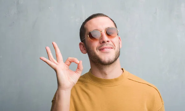 Homem Caucasiano Jovem Sobre Parede Grunge Cinza Usando Óculos Sol — Fotografia de Stock