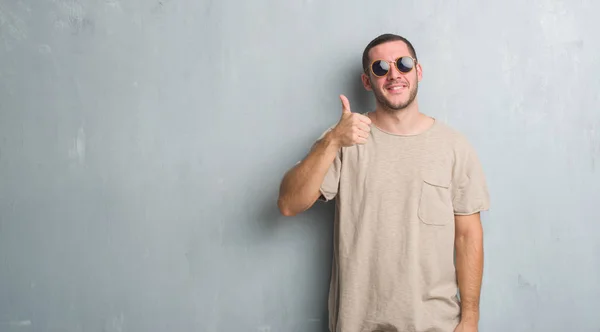 Homem Caucasiano Jovem Sobre Parede Grunge Cinza Usando Óculos Sol — Fotografia de Stock