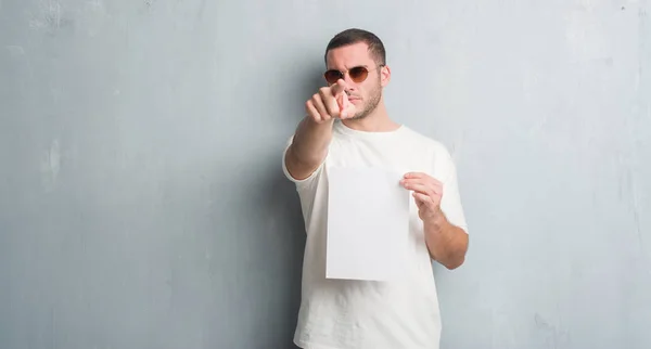 Kaukasische Jongeman Grijs Grunge Muur Blanco Papier Wijzen Met Vinger — Stockfoto