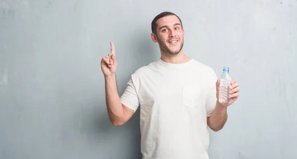 Kaukasische Jongeman Grijs Grunge Muur Bedrijf Fles Water Verrast Met — Stockfoto