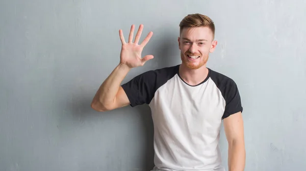 Joven Pelirrojo Hombre Sobre Gris Grunge Pared Mostrando Apuntando Hacia —  Fotos de Stock