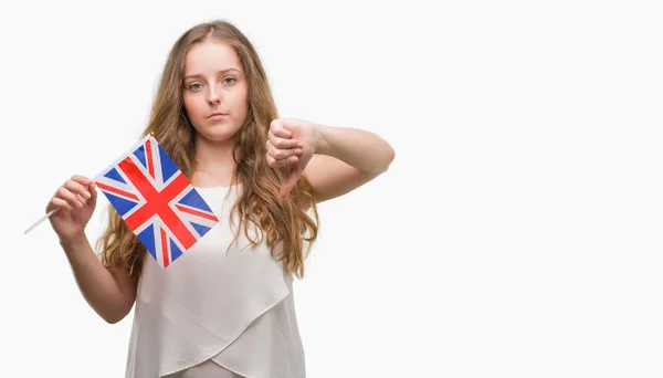 怒った顔 ダウン親指で嫌悪感を示すマイナス記号 拒絶反応の概念と英国の国旗を保持している若いブロンドの女性 — ストック写真