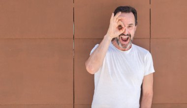 Üst düzey yakışıklı ile mutlu yüz el parmaklarının arasından seyir göz üzerinde ok işaretiyle yapıyor gülümseyen duvardan ayakta