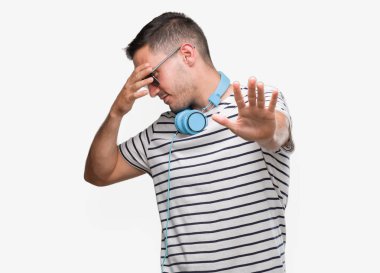 Yakışıklı genç giyen kulaklık elleriyle gözlerini kapsayan adam ve stop jest ile acı ve korku ifadesi. Utandım ve negatif kavramı.