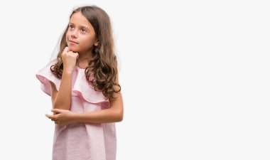 Esmer Latin kız çene düşünme hakkında soru, dalgın ifade üzerine el ile pembe elbise giymiş. Düşünceli yüzüyle gülümsüyor. Şüphe kavramı.