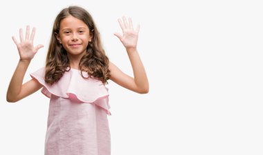 Esmer Latin kız pembe elbise gösterme ve parmakları ile işaret giyiyor kendinden emin ve mutlu gülümseyerek süre on numara.