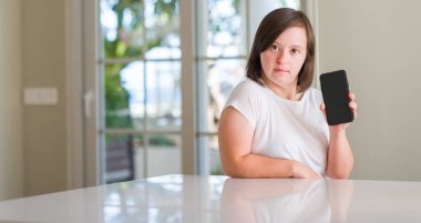 Down sendromu kadın evde akıllı yüzünde ciddi düşünme emin bir ifade ile smartphone kullanarak