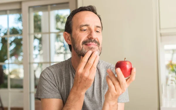 Hombre Mediana Edad Comiendo Manzana Roja Saludable Cara Seria Pensando — Foto de Stock