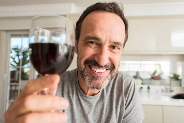立っていると自信を持って歯を見せて笑顔で笑っている幸せそうな顔でワインのガラスを飲む中年男性 — ストック写真