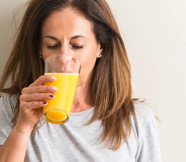 中年の女性がスマートの顔は深刻な思考に自信を持って式にガラスのオレンジ ジュースを飲む — ストック写真
