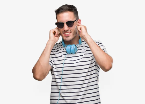 Joven Guapo Con Auriculares Cubriendo Las Orejas Con Los Dedos — Foto de Stock