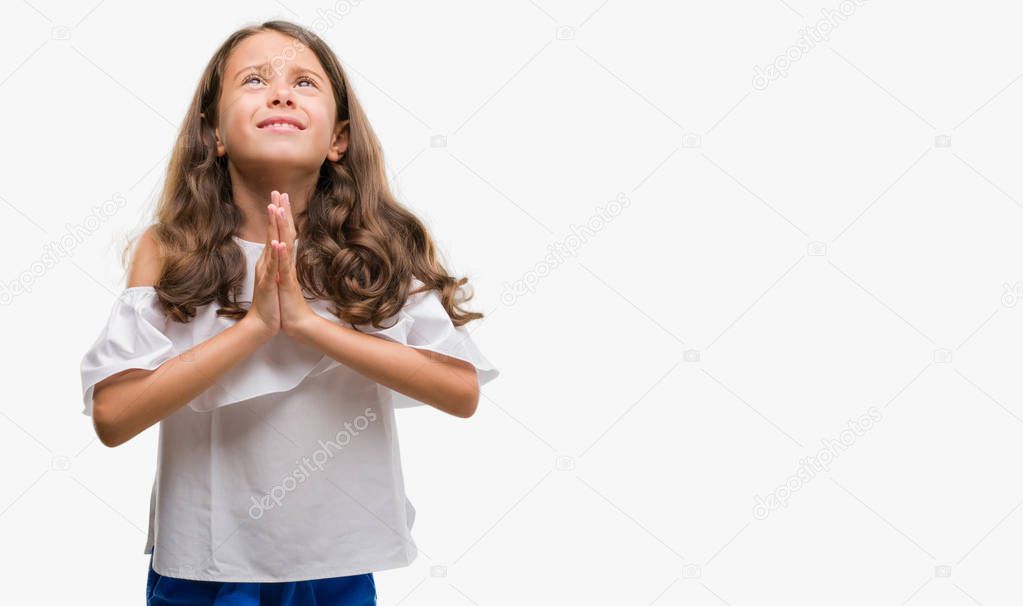 Brunette hispanic girl begging and praying with hands together with hope expression on face very emotional and worried. Asking for forgiveness. Religion concept.