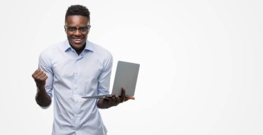 Duygu tezahürat genç Afro-Amerikalı işadamı gurur çığlık ve zafer ve başarı çok heyecanlı, kutluyor bilgisayar dizüstü kullanarak