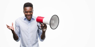 Genç Afro-Amerikan adam tutarak büyük gülümseme ile çığlık zaferini kutluyor çok mutlu ve heyecanlı, kazanan ifade megafon ve ellerini kaldırdı