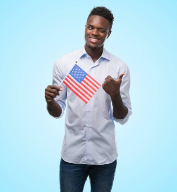 El ve parmak ile yukarı dönük mutlu yüz gülümseyen ile ABD bayrağı tutan genç Afro-Amerikan adam