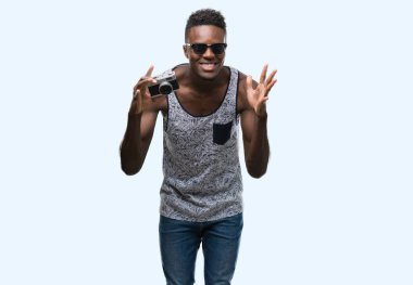 Kocaman bir gülümseme ile çığlık zaferini kutluyor ve ellerini kaldırdı vintage fotoğraf makinesi çok mutlu ve heyecanlı, kazanan ifade tutan genç Afro-Amerikan adam