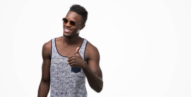 Genç Afro-Amerikan adam giyen güneş gözlüğü ok işareti yapıyor büyük gülümseme ile mutlu parmak ile mükemmel işaret parmak