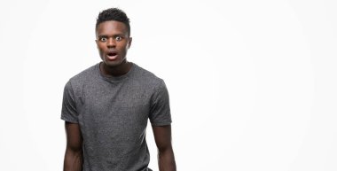 Korkuyor ve şok sürpriz ifade, korku ve heyecan yüz ile gri t-shirt giyen genç Afro-Amerikan adam.