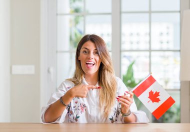 Genç kadın evde Kanada bayrağı çok mutlu el ve parmak ile işaret tutan