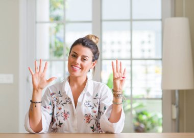 Genç kadın evde gösterilen ve parmak dokuz ile gülümseyen ise kendinden emin ve mutlu yukarı dönük.