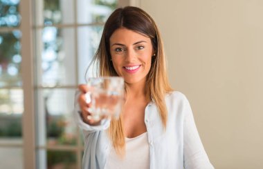 Bir bardak su evde tutarken gülümseyen güzel ve genç birbayan. Yaşam tarzı kavramı.