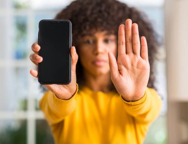 Afrikalı-Amerikalı kadın açık eliyle dur işareti ile ciddi ve kendine güvenen ifade, savunma jest yapıyor Smartphone kullanarak